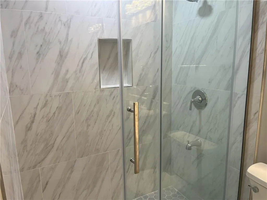 Bathroom featuring a marble finish shower and toilet