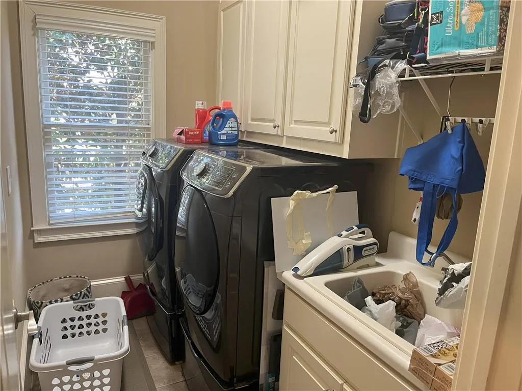 Washroom featuring cabinet space, tile patterned flooring, and washing machine and dryer