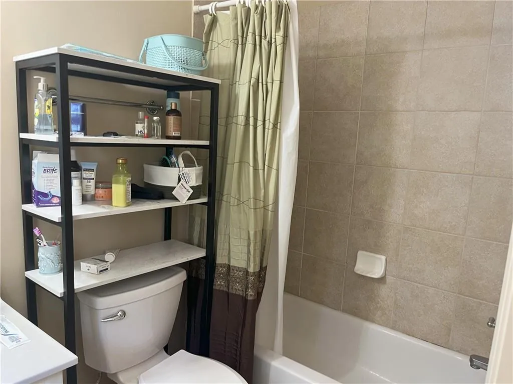 Full bathroom featuring shower / bath combination with curtain and toilet