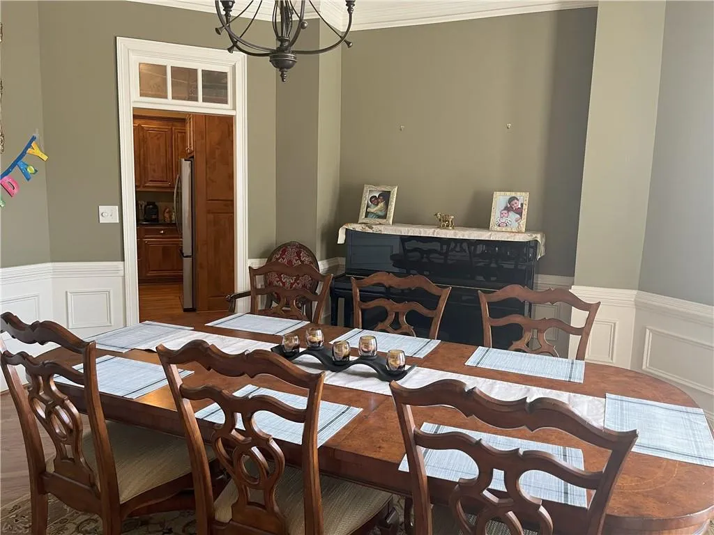 Dining space with a decorative wall, a wainscoted wall, ornamental molding, and a chandelier