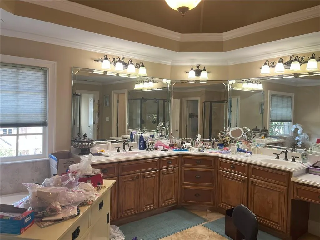 Full bathroom featuring ornamental molding, a shower stall, double vanity, and light tile patterned flooring