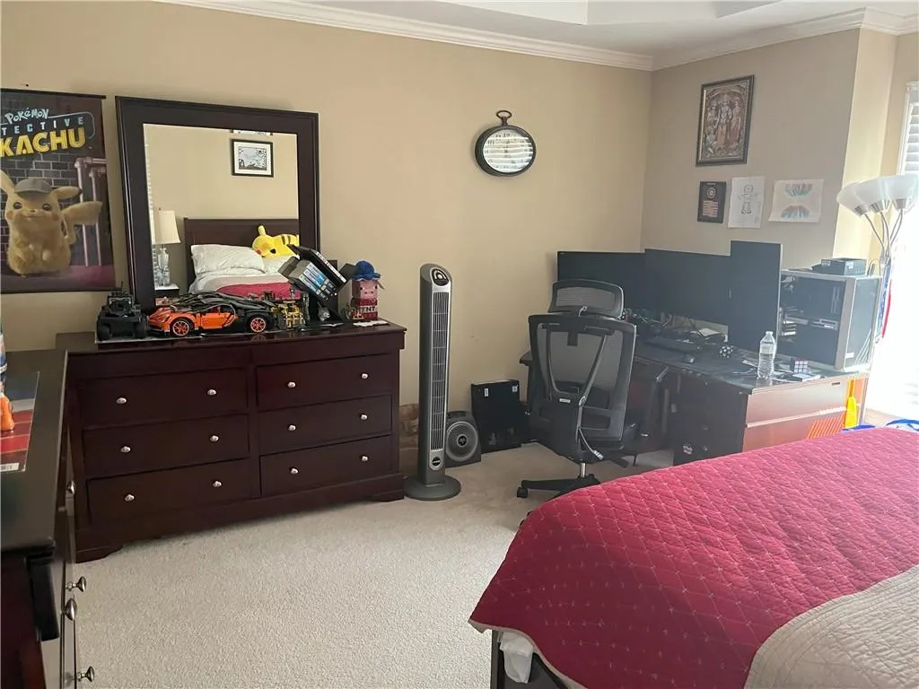 Carpeted bedroom with crown molding and an office area