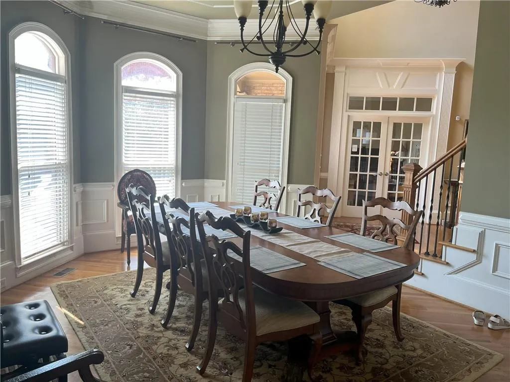Dining area with a wainscoted wall, french doors, a decorative wall, plenty of natural light, and wood finished floors