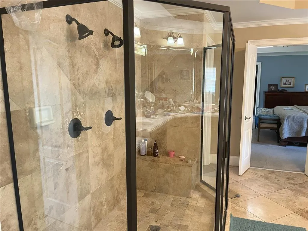 Ensuite bathroom with a shower stall, crown molding, and tile patterned floors