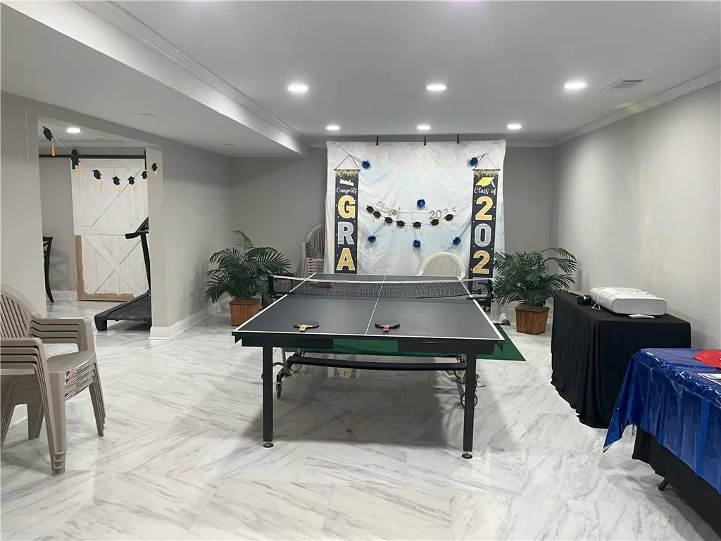 Game room featuring ornamental molding, recessed lighting, a barn door, and marble finish floors