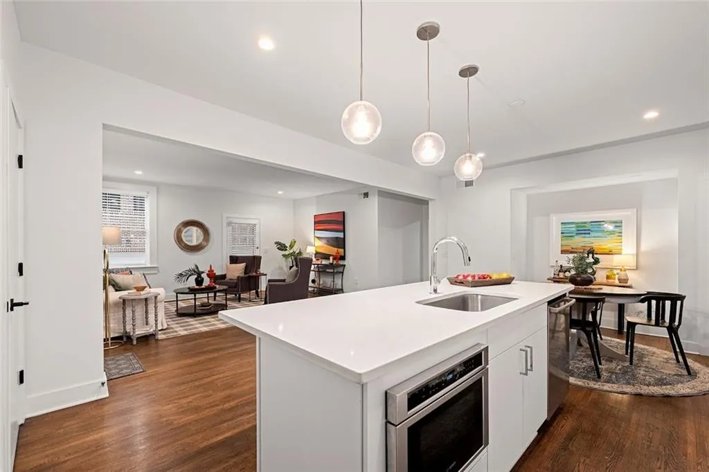 Kitchen featuring hanging light fixtures, a center island with sink, sink, and dark hardwood / wood-style floors