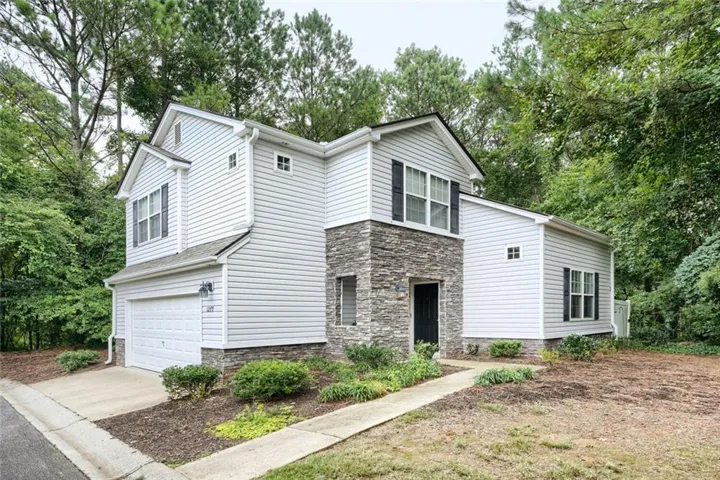 Two-story home with a prominent stone facade accent and light siding
