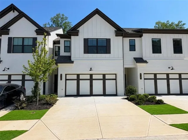 Modern townhome exterior featuring white painted brick and vertical siding