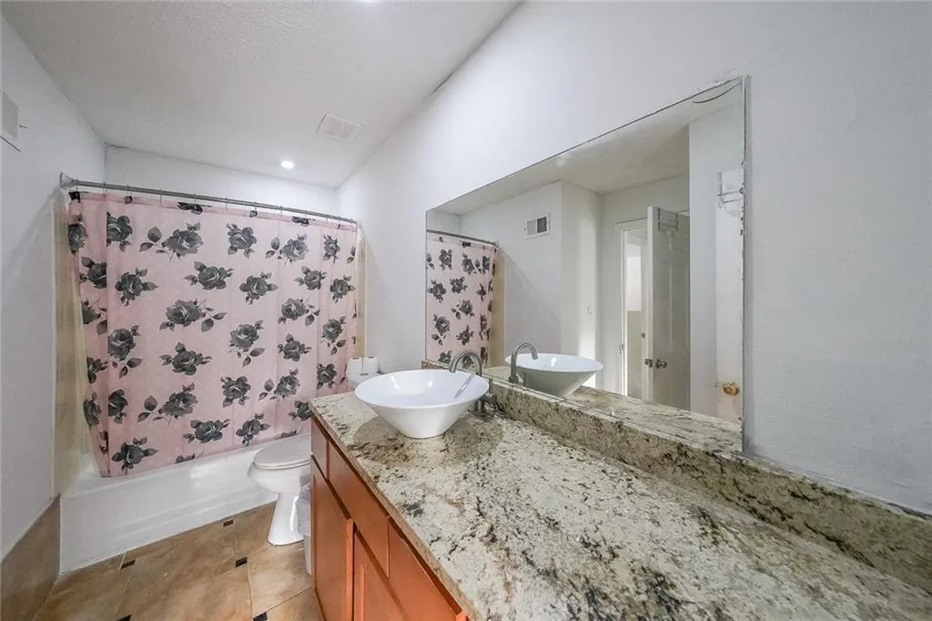 Full bath featuring vanity, shower / tub combo with curtain, and light tile patterned floors