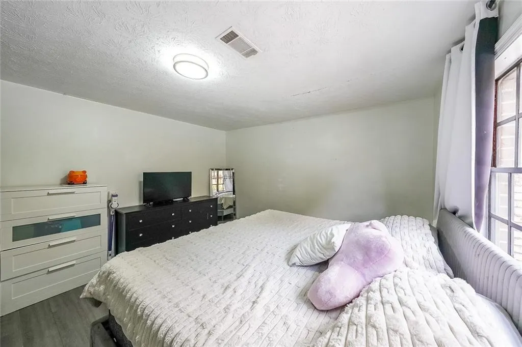 Bedroom featuring a textured ceiling, multiple windows, and dark wood finished floors