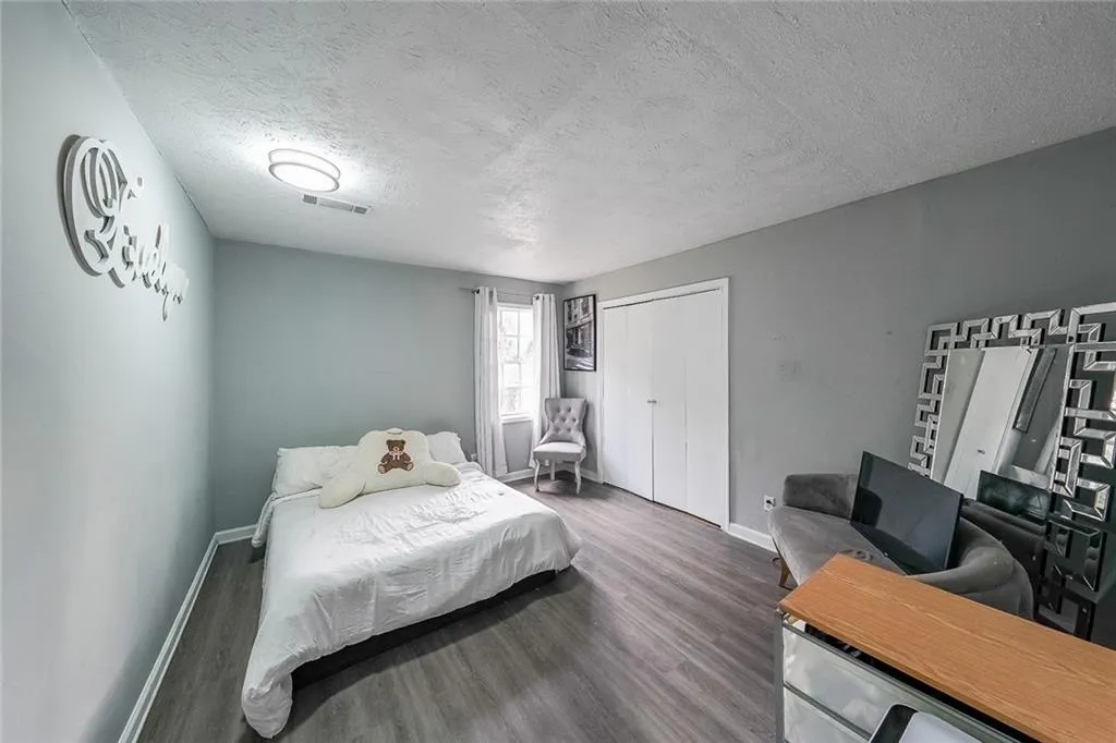 Bedroom with a textured ceiling, wood finished floors, and a closet