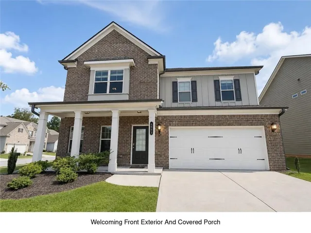 Brick and siding exterior with a covered porch, two-car garage, and established landscaping