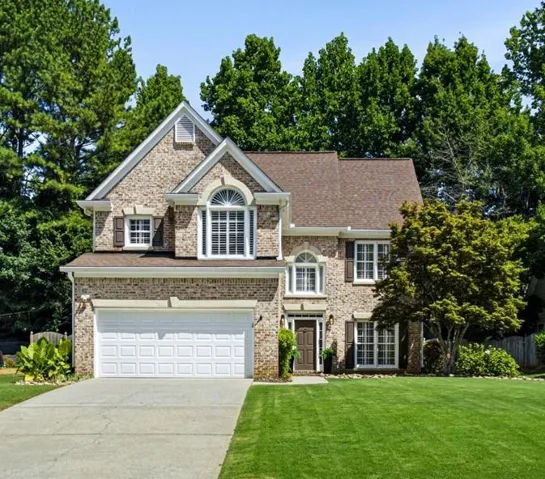 Brick facade residence with a two-car garage, arched windows, and a gabled roof