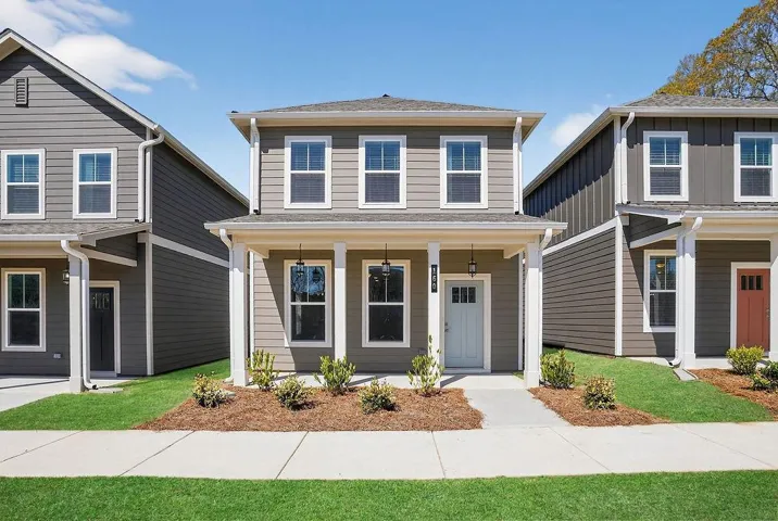 Two-story residence featuring siding exterior, a covered porch with square columns, and a light-colored front door with glass lites