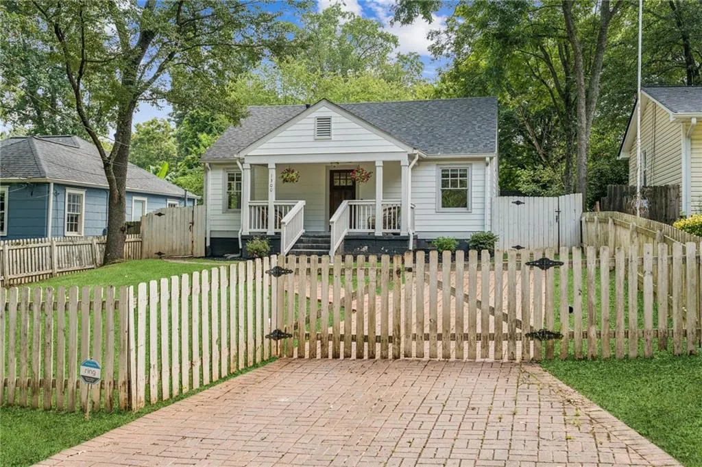 View of front of property featuring a gate, a porch, and a shingled roof