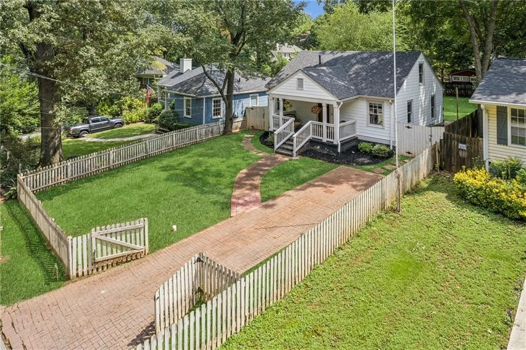 View of front facade featuring roof with shingles, view of scattered trees, and a fenced backyard