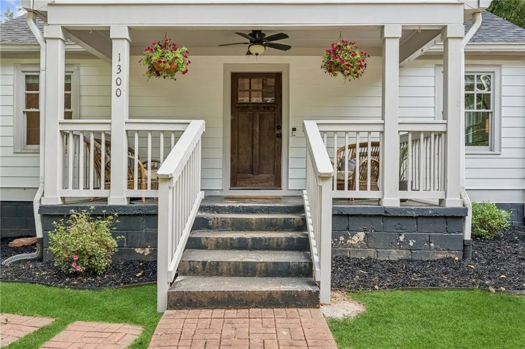 View of exterior entry featuring a shingled roof, covered porch, and ceiling fan
