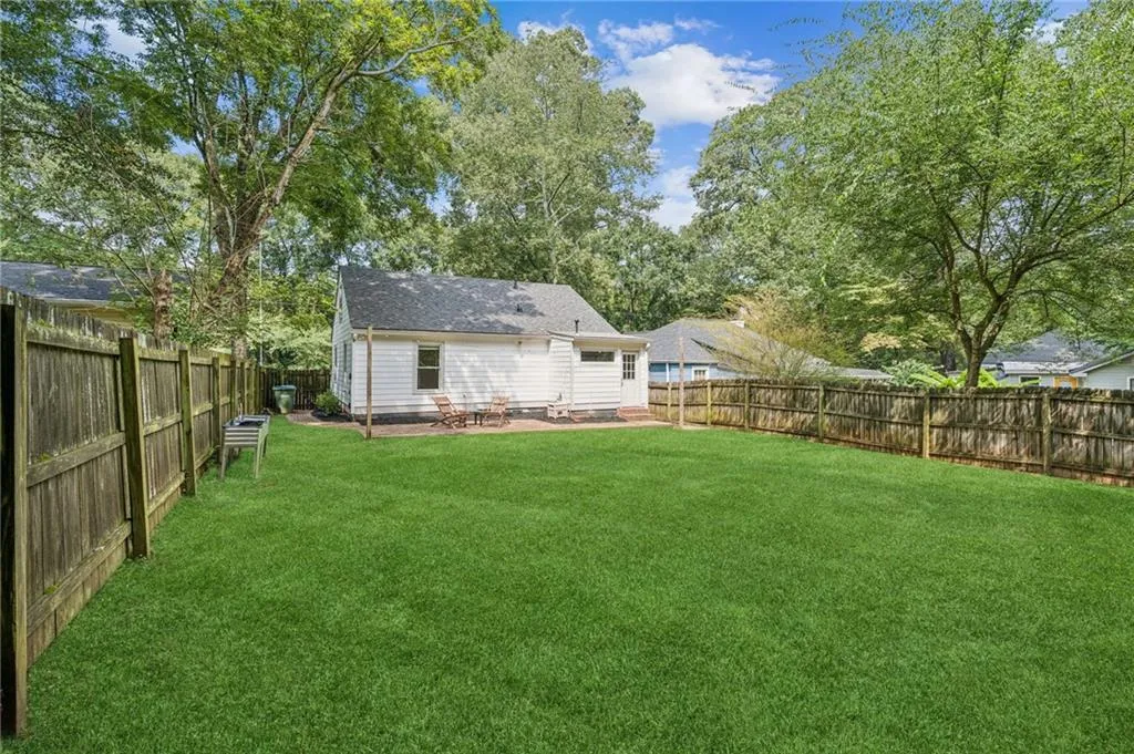 Fenced backyard with a patio area and view of scattered trees