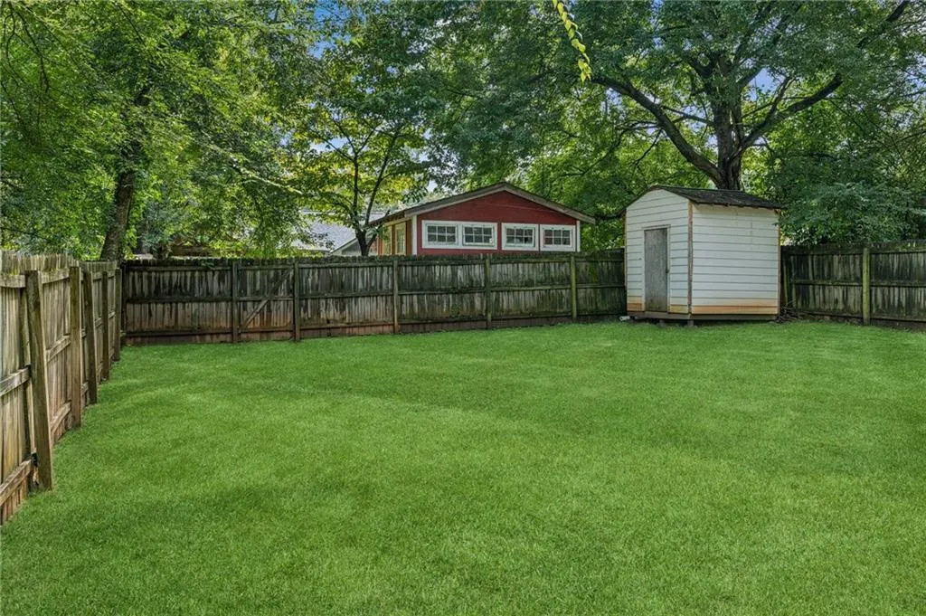 Fenced backyard featuring a storage unit