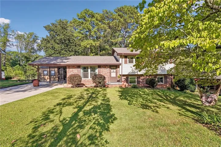 Split-level residence featuring a brick facade, white siding, and a covered carport