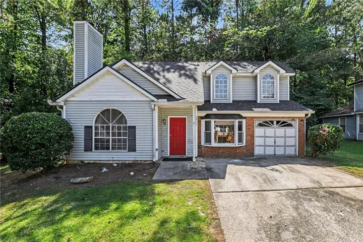 Light-toned siding exterior with a red front door, prominent bay window, and a single-car garage
