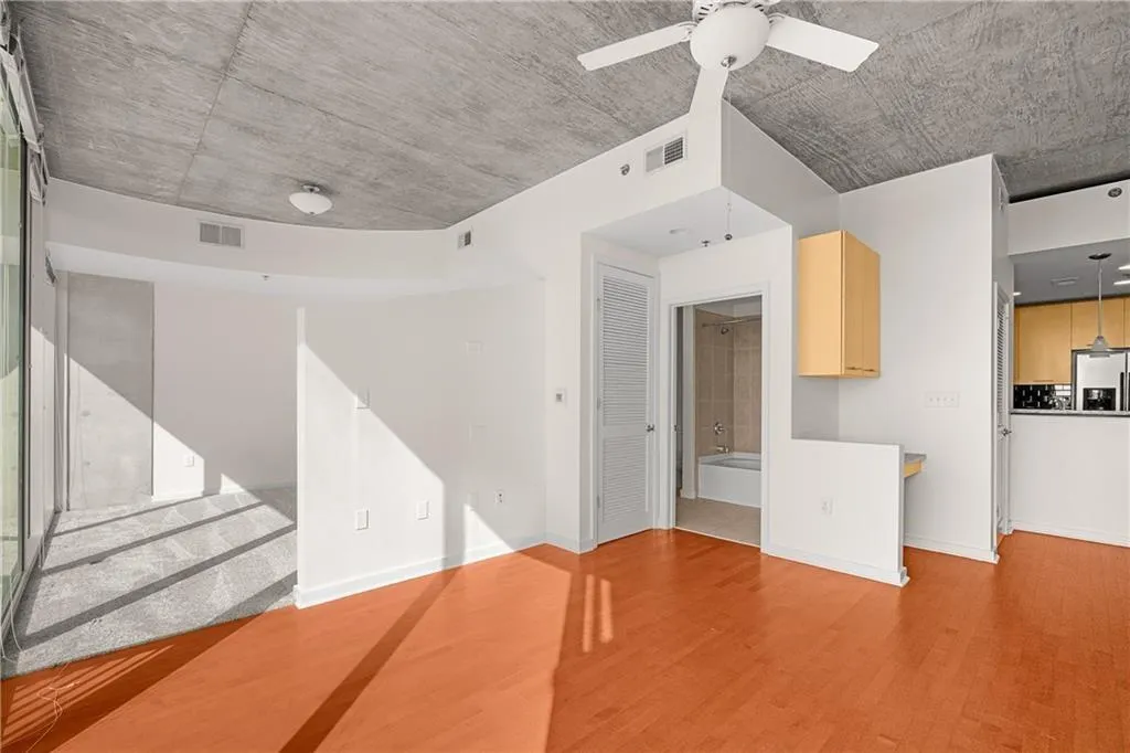 Unfurnished living room with a ceiling fan, wood finished floors, visible vents, and baseboards