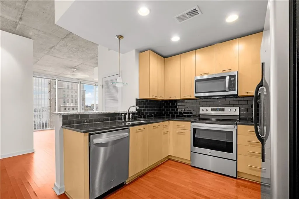 Kitchen featuring a peninsula, light brown cabinets, visible vents, and appliances with stainless steel finishes