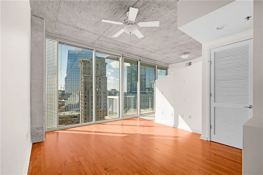 Unfurnished room with visible vents, baseboards, ceiling fan, expansive windows, and wood finished floors