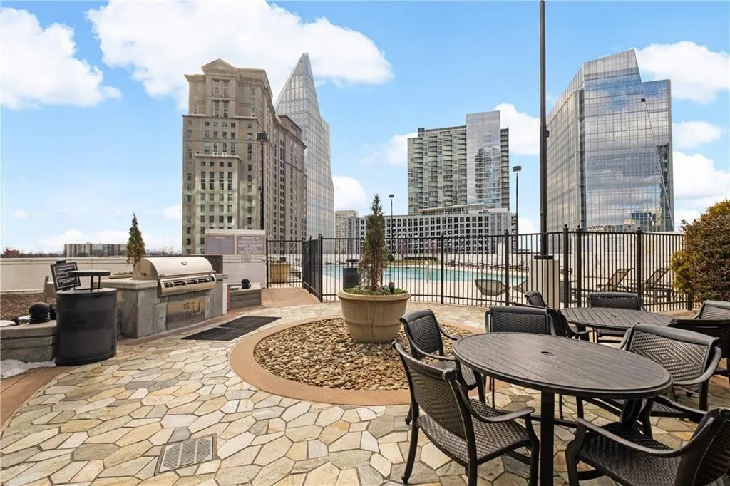 View of patio / terrace featuring a view of city, fence, a community pool, a grill, and an outdoor kitchen