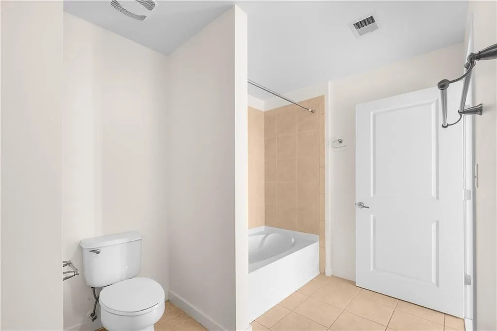 Bathroom with visible vents, baseboards, tile patterned flooring, bathtub / shower combination, and toilet