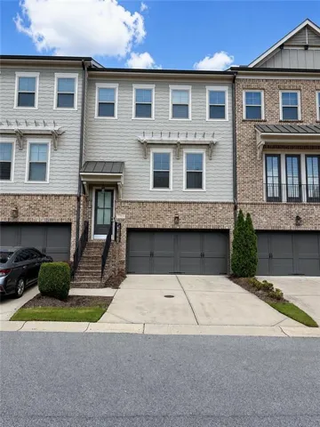Townhome exterior featuring brick and horizontal siding, multiple windows, and a two-car garage