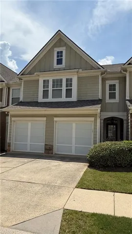 Two-car garage with white doors, stone accents, and a concrete driveway