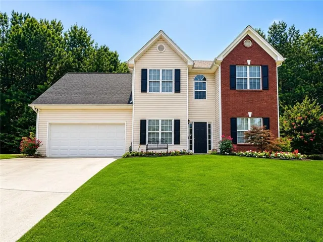 Two-story residence featuring a brick and siding exterior, an arched window, a two-car garage, and a concrete driveway