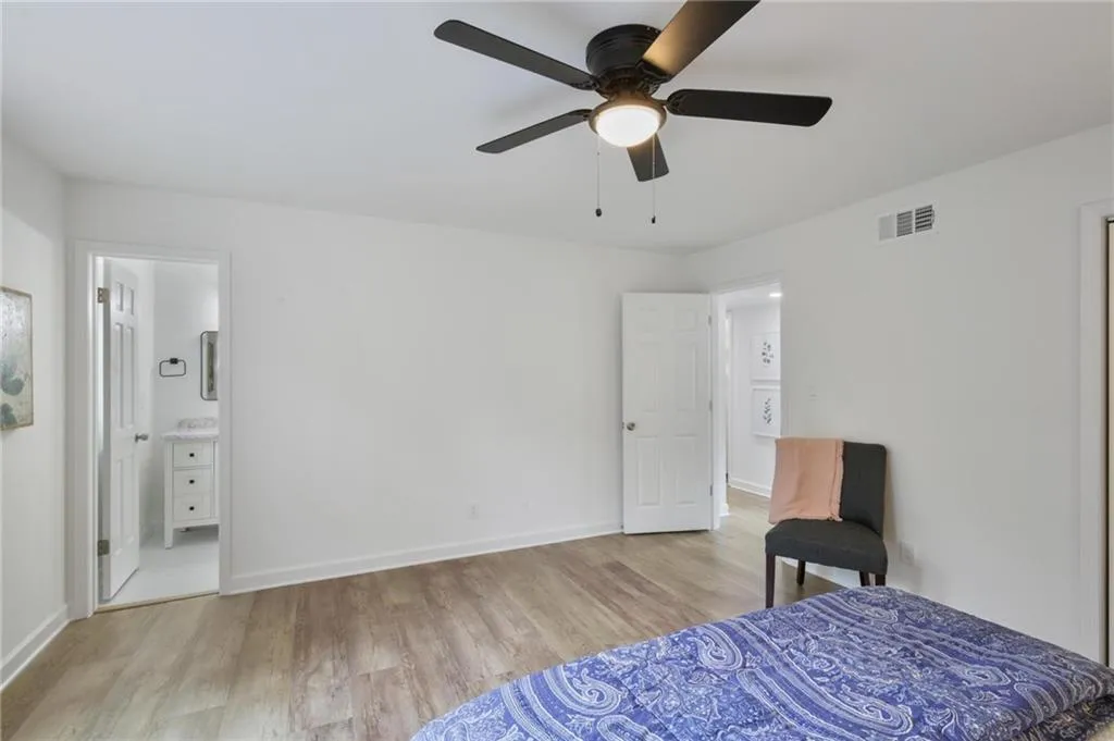 Bedroom with ensuite bath, ceiling fan, and light hardwood / wood-style floors