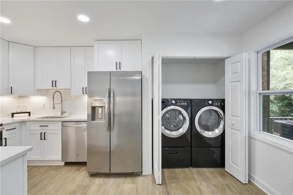 Washroom with washer and clothes dryer, sink, and light wood-type flooring