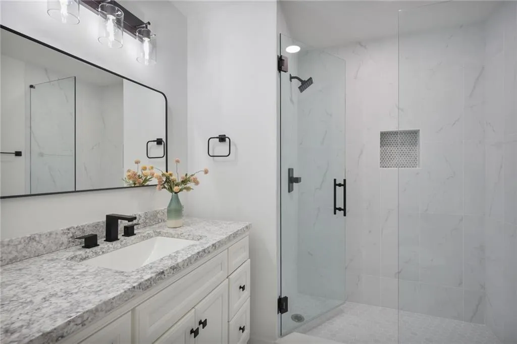 Bathroom featuring a shower with shower door and vanity