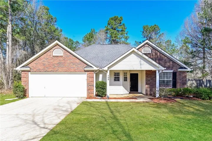 Brick and siding exterior with a covered entry, attached garage, and mature landscaping