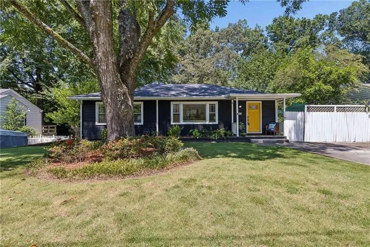 Modern ranch home featuring a sprawling manicured lawn, mature shade trees, and a black exterior with contemporary window treatments