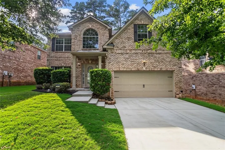 Brick exterior with a prominent arched window, attached two-car garage, and a covered entry