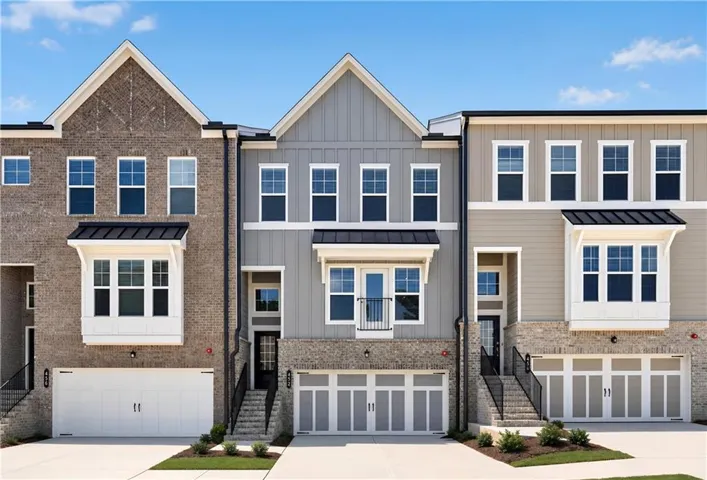 Modern townhome exterior featuring brick and siding finishes, multiple windows, and a two-car garage