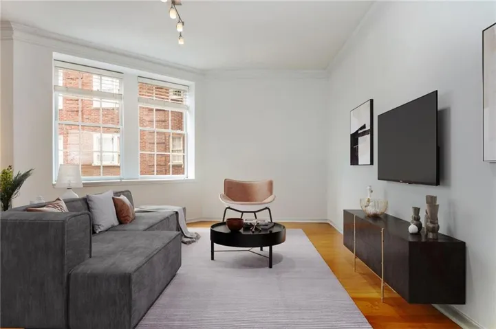 Wood-finish flooring, white walls, crown molding, double windows with grids, and a floating entertainment console