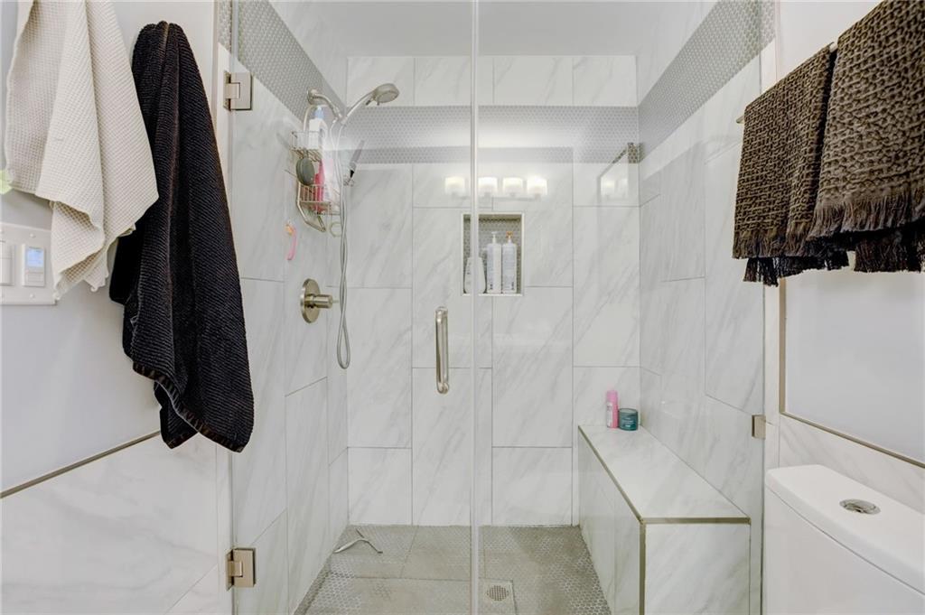Bathroom with toilet, tile walls, and a shower with shower door