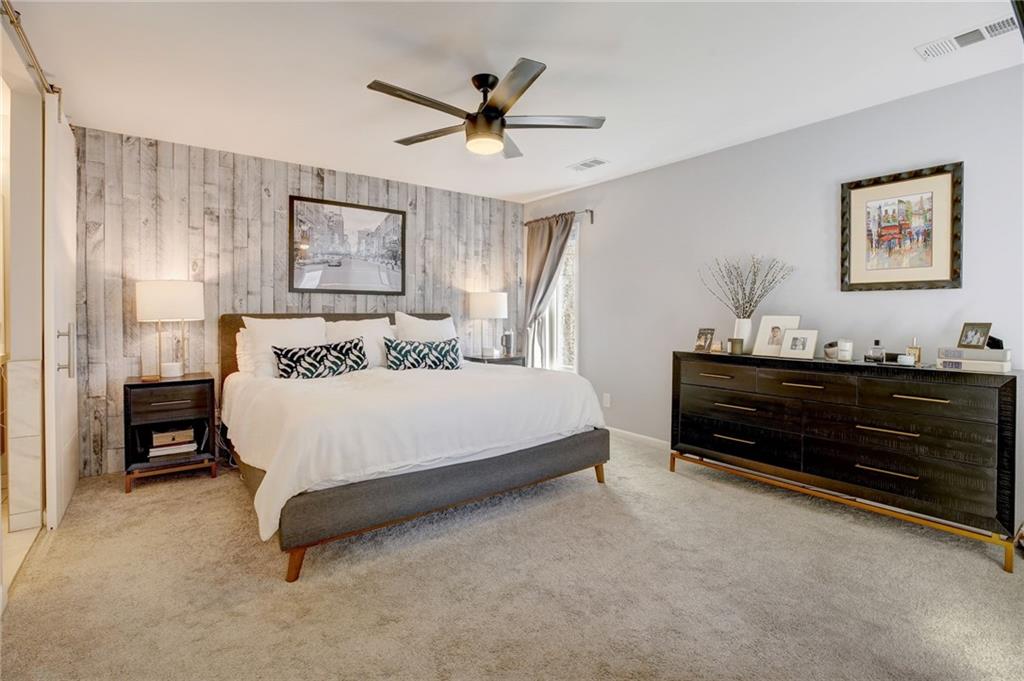 Carpeted bedroom featuring ceiling fan and wood walls