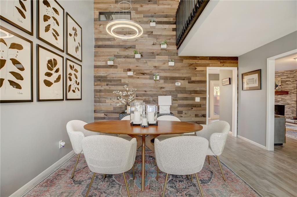Dining area with a stone fireplace, wood walls, and light wood-type flooring