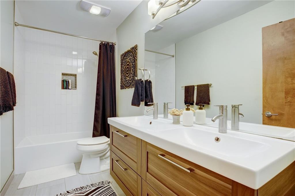 Full bathroom with dual sinks, toilet, shower / tub combo with curtain, large vanity, and tile flooring