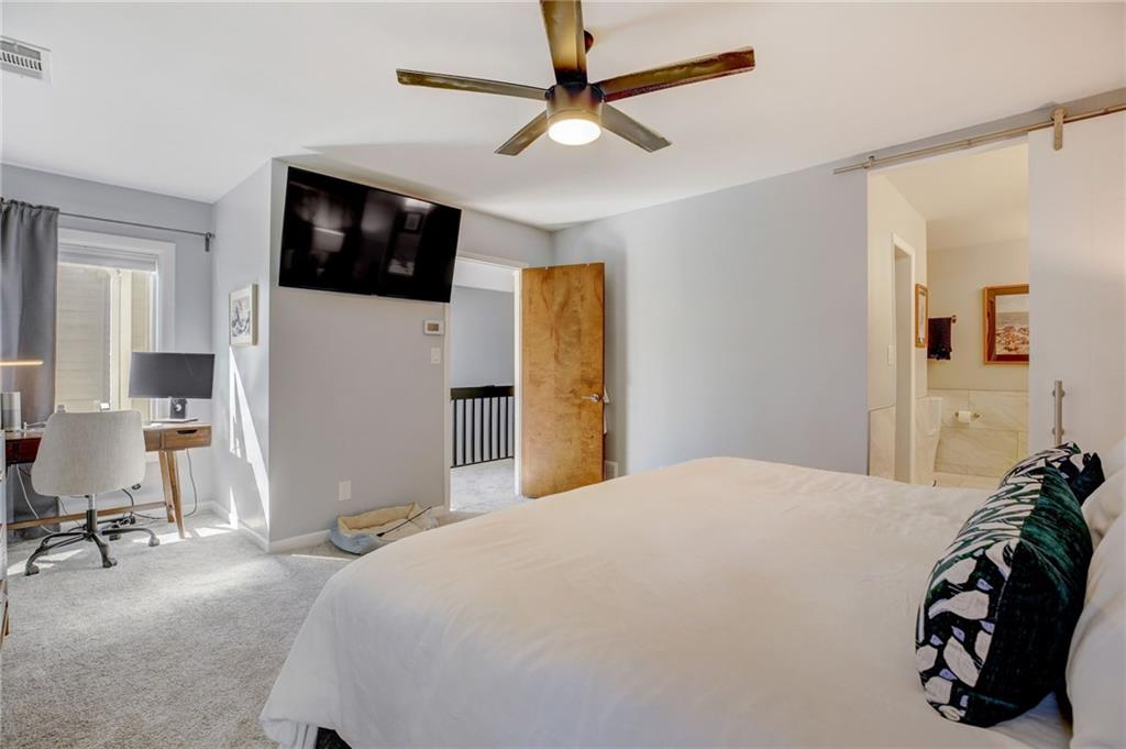 Carpeted bedroom featuring ceiling fan and ensuite bath