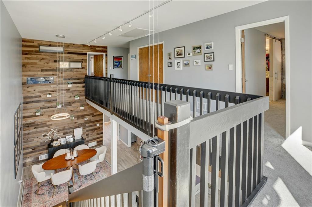 Hall with wood walls, light colored carpet, and track lighting