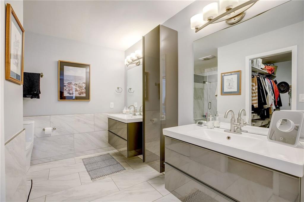 Bathroom featuring a shower with door, dual bowl vanity, and tile flooring