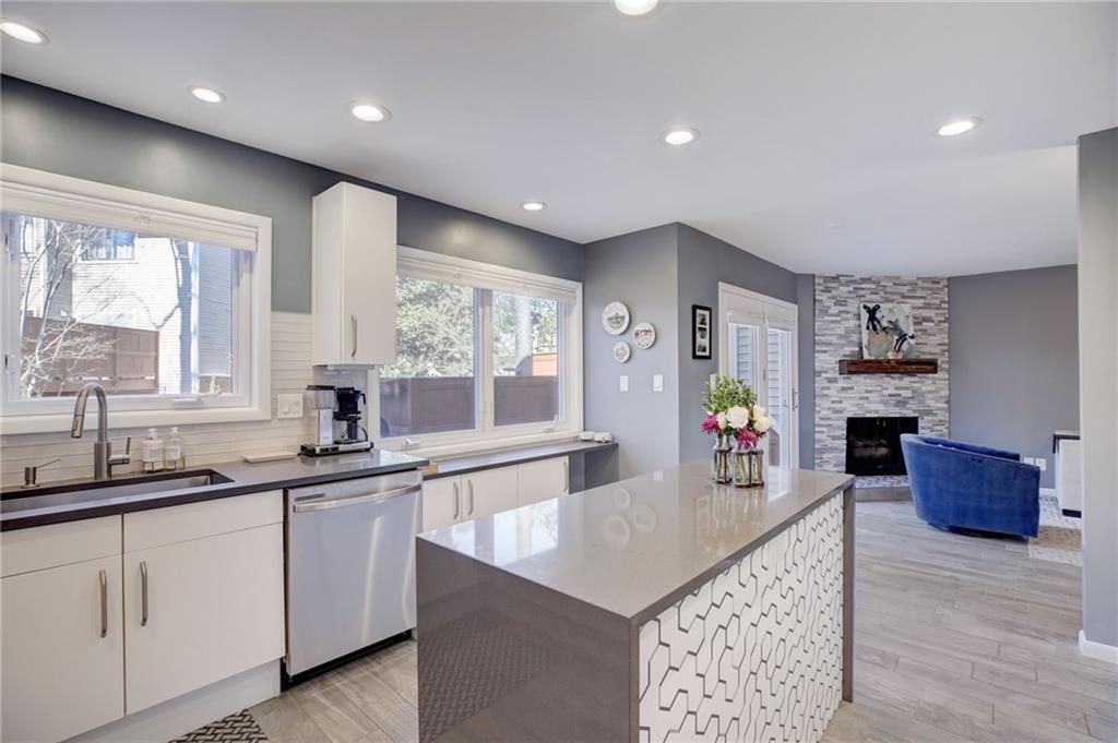 Kitchen with dishwasher, white cabinets, a center island, sink, and a stone fireplace