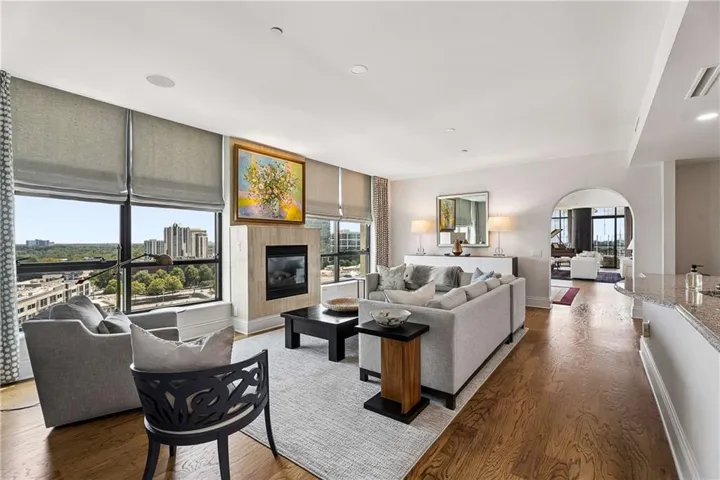 Hardwood flooring, fireplace with stone surround, recessed lighting, arched entryway, and large windows with roller shades